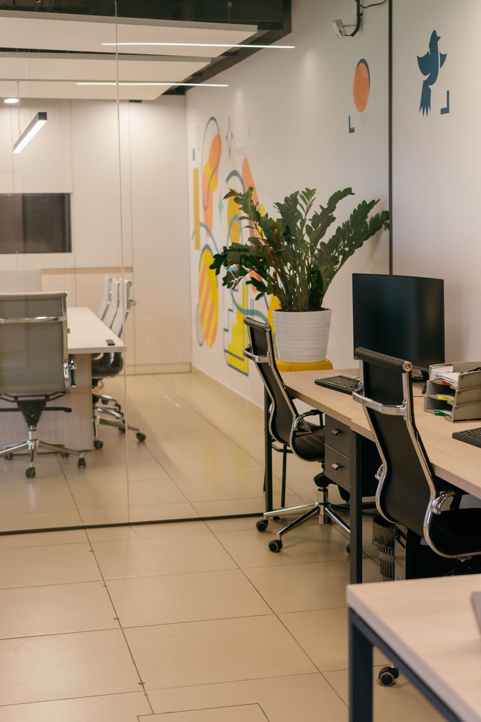Intérieur de bureau spacieux et contemporain avec cloisons vitrées, mobilier élégant et œuvres murales colorées.